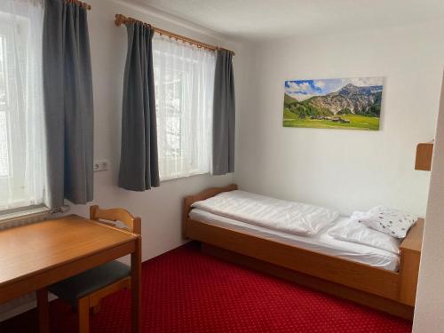 um quarto com uma cama, uma secretária e uma janela em Appartements Wieseneck - beste Lage inklusive Sommercard em Ramsau am Dachstein