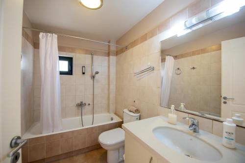 a bathroom with a sink and a tub and a toilet at Portela Apartments Kampoula in Keratokampos