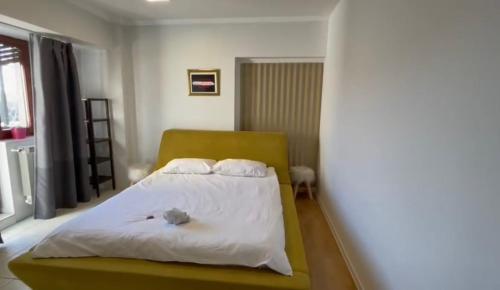 sypialnia z białym łóżkiem z żółtym zagłówkiem w obiekcie apartment 26 old town w Bukareszcie