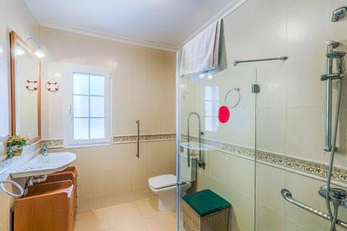 a bathroom with a shower and a toilet and a sink at Villa Tuduri in Binibeca