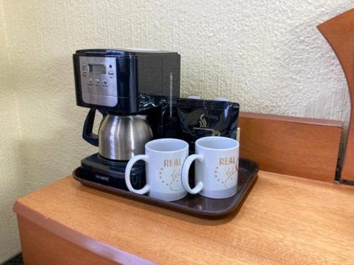 a coffee maker and two mugs on a tray on a counter at Hotel Real del Sur in Mexico City