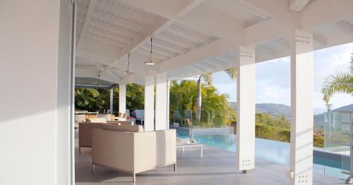 an open living room with a view of a pool at Villa Coco Cannelle in Deshaies