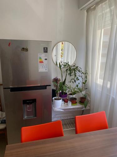cocina con nevera de acero inoxidable y sillas de color naranja en departamento monoambiente en Mar del Plata