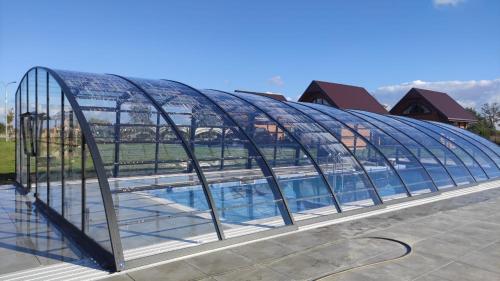 a glass greenhouse with a swimming pool inside at Wakacyjna Osada in Jezierzany