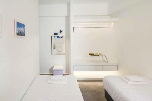 Cette chambre blanche dispose de deux lits et d'une fenêtre. dans l'établissement Villa Paradiso Ena, à Agia Pelagia