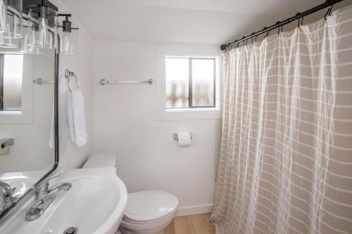 a white bathroom with a toilet and a sink at Cozy 2 Bedroom Home, Private Backyard with Hot Tub in Seaview