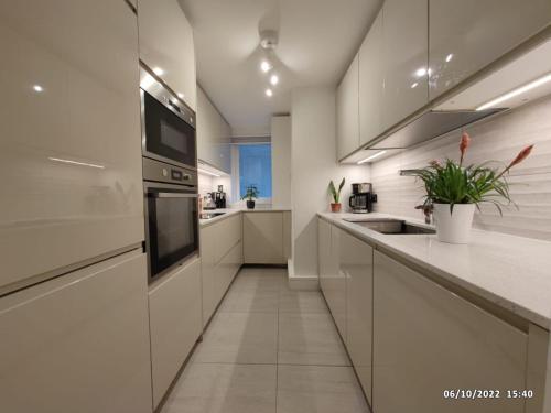 una cocina con armarios blancos y fregadero en Luxury Apartment South Kensington en Londres