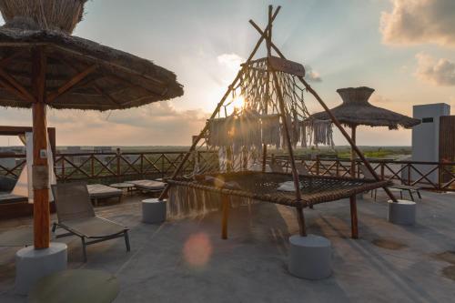 a patio with chairs and umbrellas on a roof at Naala Tulum in Tulum