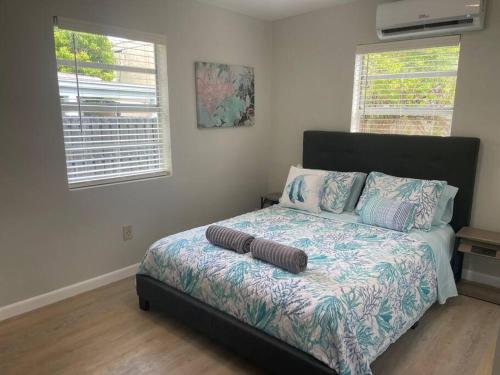 1 Schlafzimmer mit einem Bett mit einer Bettdecke und 2 Fenstern in der Unterkunft Luxury House with delightful beach Style! in Dania Beach