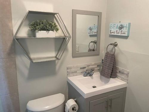 a bathroom with a toilet and a sink and a mirror at Luxury House with delightful beach Style! in Dania Beach
