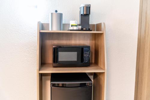 a microwave on a wooden shelf next to a wall at Holiday Inn Express & Suites Phoenix - Mesa West, an IHG Hotel in Mesa