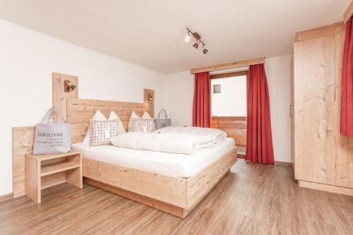 Schlafzimmer mit einem großen Bett und roten Vorhängen in der Unterkunft Ferienwohnungen Winnebach in Gries