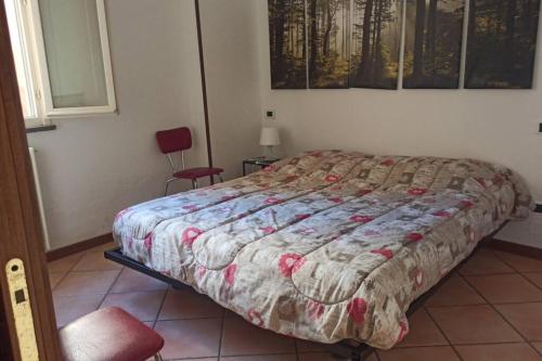 een slaapkamer met een bed en een rode stoel bij porta merlonia house trilocale in Forlì
