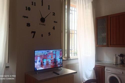 een tv zittend op een tafel met een klok aan de muur bij porta merlonia house trilocale in Forlì