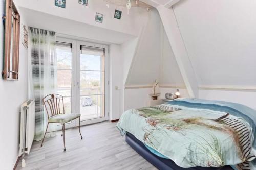 Un dormitorio con una cama y una silla y una ventana. en Vakantiehuis met Luxe Tuin dichtbij het strand, en Kamperland
