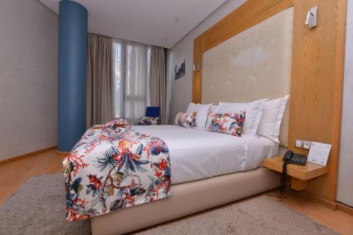 カサブランカにあるLe 135 appart hotelのベッドルーム1室(花柄のベッドカバー付きの大型ベッド1台付)