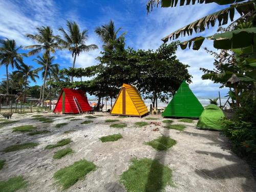 three colored tents on a beach with palm trees at Camping Gnomo Místico in Olivença