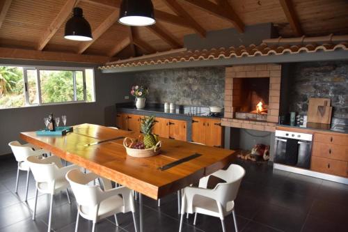 a kitchen with a large wooden table and a fireplace at Quinta do Brasil in Arco da Calheta