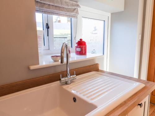 a white sink in a kitchen with a window at Tawny Cottage in Scarborough