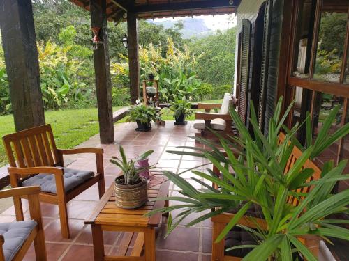a porch with chairs and potted plants on it at Sitio Santa Clara in Teresópolis