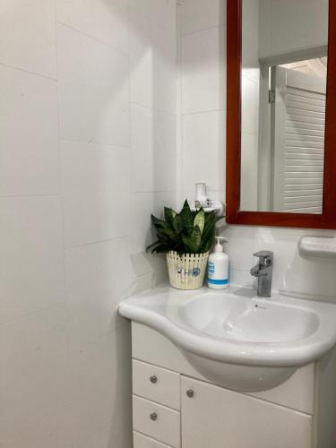 Baño blanco con lavabo y espejo en Casa Paraíso, en Guayaquil