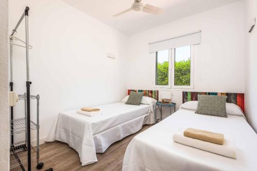 a white room with two beds and a window at Villa Xaloc in Port d'Addaia