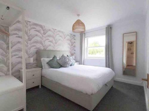 a bedroom with a large white bed with a tropical wallpaper at 2 Bed Cottage Barnstaple North Devon Dog-Friendly! in Barnstaple