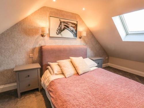a attic bedroom with a bed and a window at The Stables in Scarborough