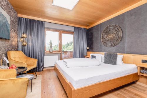 a bedroom with a bed and a chair at Boutique-Pension Jägerwirt in Scheffau am Wilden Kaiser