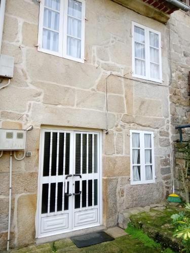 Casa de piedra con puerta blanca y 2 ventanas en El Rincón de Sara, en Tui