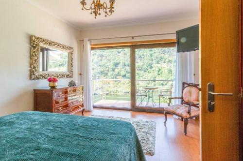 um quarto com uma cama, uma janela e uma cadeira em Casa da Barragem Douro em Cinfães