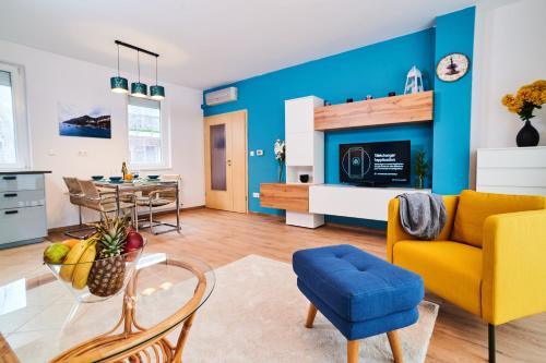 a living room with a yellow couch and a blue wall at FEEL HOME DeLuxe CORVIN -FREE PARKING-AC-Elevator in Budapest