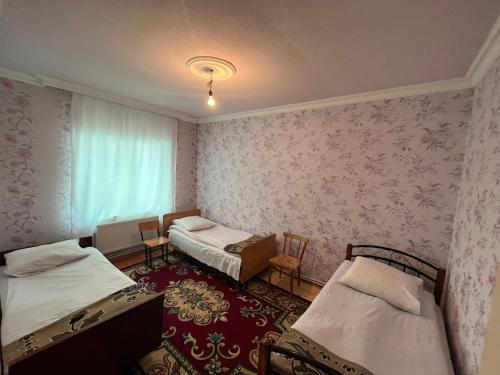 Cette petite chambre comprend 2 lits et une fenêtre. dans l'établissement Orchard, à Quba