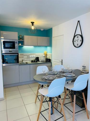 une cuisine avec une table et des chaises et une horloge au mur dans l'établissement Le colibri, à Dinard
