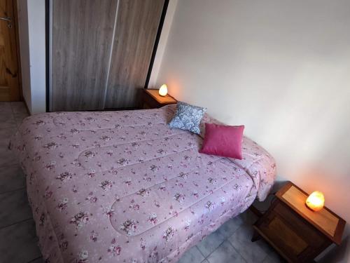 a bedroom with a pink bed with two pillows at Departamento Centrico in El Bolsón
