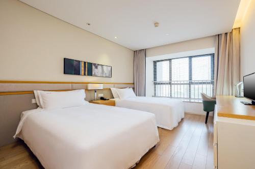 a hotel room with two beds and a desk at Holiday Inn & Suites Suzhou Yangcheng Lake, an IHG Hotel in Suzhou