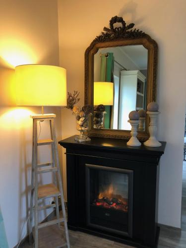 a fireplace with a mirror and a chair and a lamp at Gîte La Sellerie in Les Sorinières