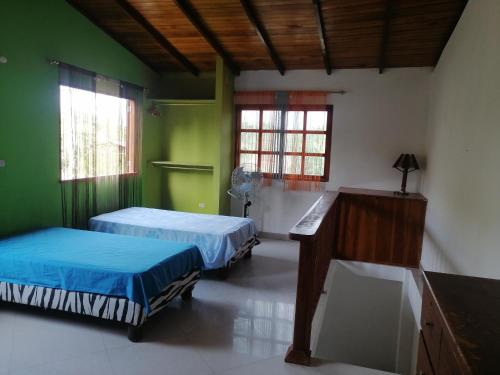 a room with two beds and a desk and windows at Casa Bony in Montañita