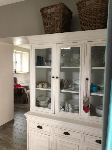 a white hutch with plates and dishes in it at Gîte La Sellerie in Les Sorinières