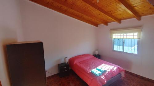 1 dormitorio con cama roja y ventana en Departamento Asaï Malargüe en Malargüe