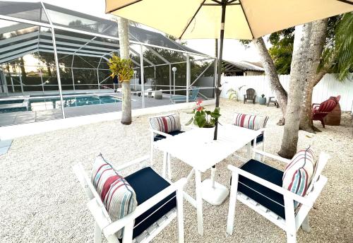una mesa y sillas blancas con sombrilla y piscina en Home in Miami, en Miami