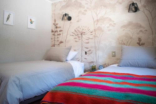 a bedroom with two beds and a colorful blanket at Cabañas Montenegro in Villarrica