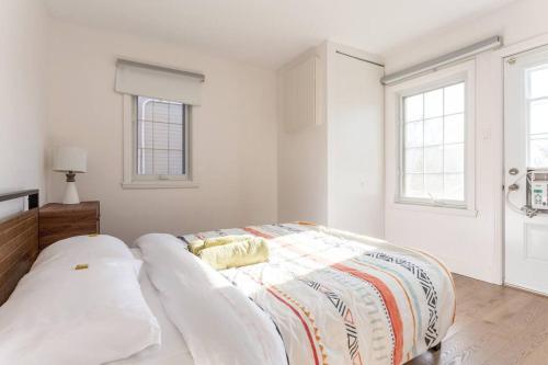 a bed in a white room with two windows at Free Parking, Beautiful 4 1/2-2 BR apartment in Montreal