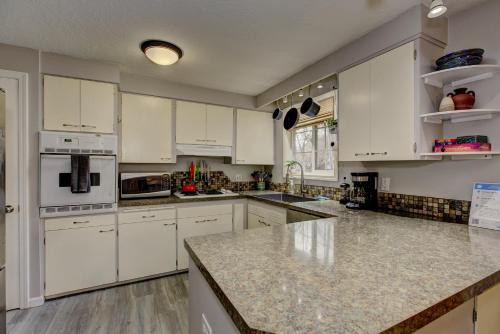 a kitchen with white cabinets and marble counter tops at Sunset Home perfect for extended stays with fully fenced in yard, designated office, two living rooms, located across from Boise Foothills and close to Bogus Basin in Boise's North End in Boise