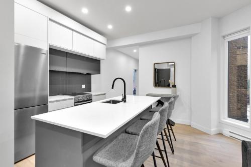a kitchen with a white counter and stools at Deluxe Suites Downtown Montreal in Montréal