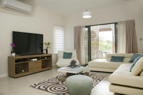 a living room with a flat screen tv and a couch at Luxury 2-bedroom apartment with shared pool 2 mins to Pereybere beach in Pereybere
