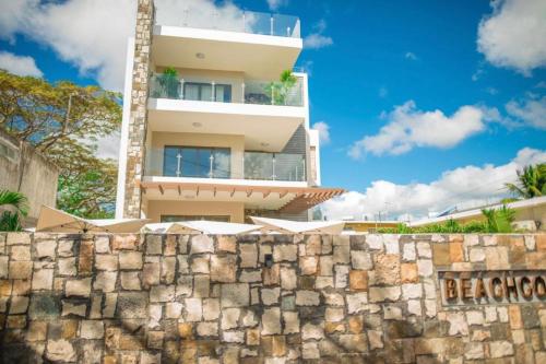 a tall building behind a stone wall with a fence at Luxury 2-bedroom apartment with shared pool 2 mins to Pereybere beach in Pereybere