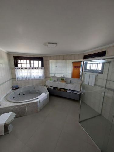 y baño grande con 2 bañeras y ducha. en Pousada Brisas do Rio, en Torres