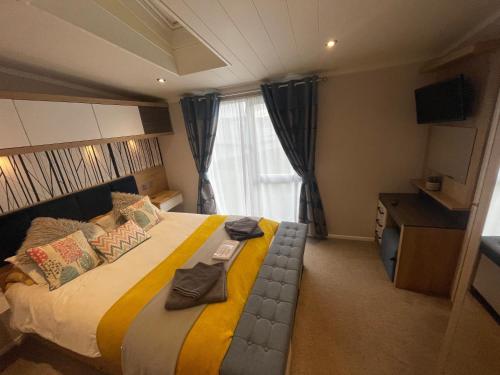 a bedroom with a large bed with towels on it at Indulgence Lakeside Lodge i3 with hot tub, private fishing peg situated at Tattershall Lakes Country Park in Tattershall