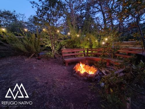 a bench sitting next to a fire in a yard at Refugio Nativo in Nevados de Chillan